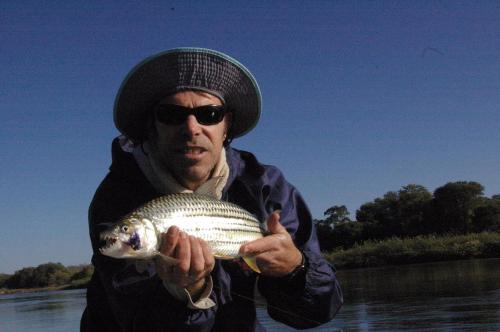 a man holding a fish in his hand on a river at Sundowner Lodge in Hwange