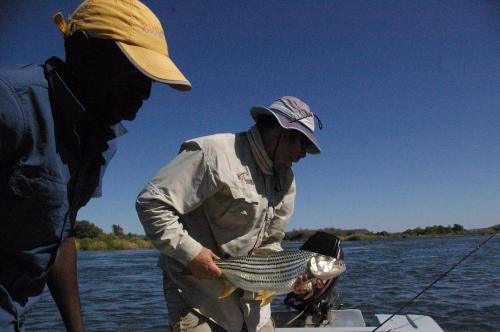 two people on a boat with a fish in the water at Sundowner Lodge in Hwange