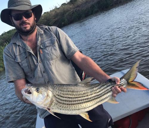 a man holding a large fish on a boat at Sundowner Lodge in Hwange