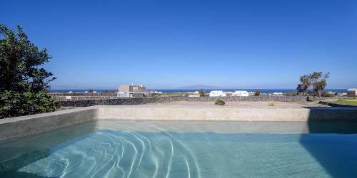 a swimming pool with the ocean in the background at Santopaz Suites in Oia