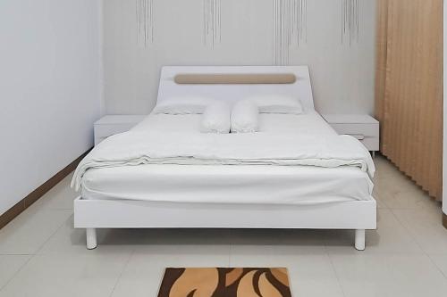 ein weißes Bett mit zwei Kissen auf einem Zimmer in der Unterkunft Angel Guest House Lembang RedPartner in Lembang