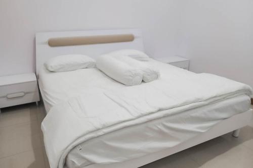 a white bed with white sheets and towels on it at Angel Guest House Lembang RedPartner in Lembang