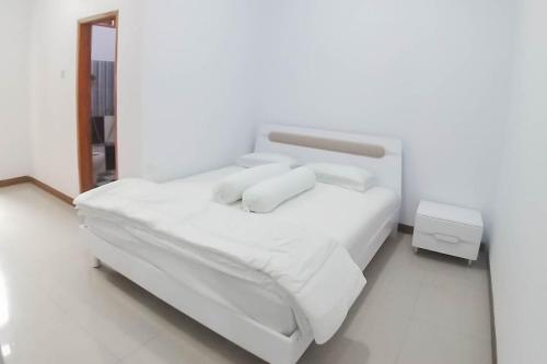 a bedroom with a white bed with white sheets and pillows at Angel Guest House Lembang RedPartner in Lembang