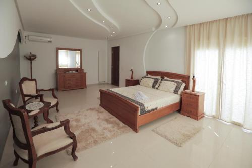 a bedroom with a bed and a chair and a window at Magnifique Villa Avec Piscine, Pour Vos Vacances ! in Monastir