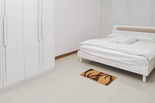 a white bedroom with a bed and a rug on the floor at Angel Guest House Lembang RedPartner in Lembang