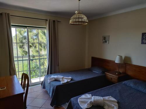 een hotelkamer met twee bedden en een raam bij Casa do Poco in Armação de Pêra