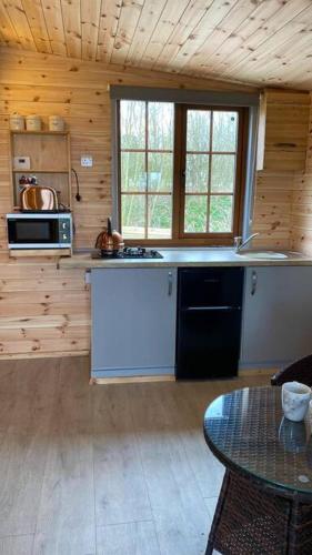 a kitchen in a wooden cabin with a counter top at Beautiful Wooden tiny house, Glamping cabin with hot tub 2 in Tuxford