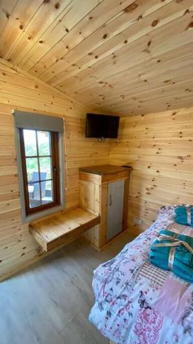 a bedroom of a wooden cabin with a bed and a window at Beautiful Wooden tiny house, Glamping cabin with hot tub 2 in Tuxford