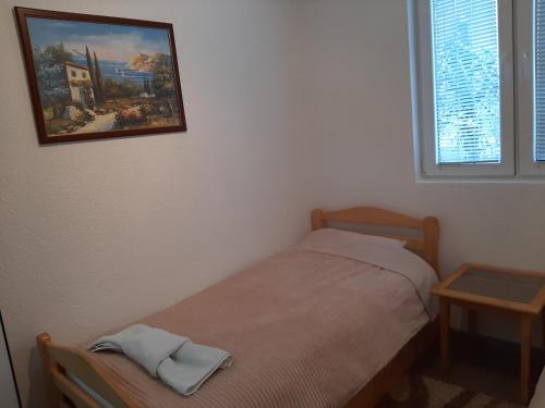 a small bedroom with a bed and a picture on the wall at Vikendica RTANJ in Rtanj