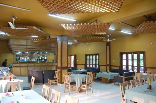 a restaurant with tables and chairs and a bar at Hotel Parkland in Sauraha