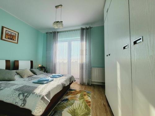a bedroom with a bed and a large window at Apartament Laurowy in Darłowo