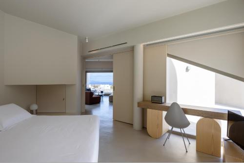 a bedroom with a bed and a desk and a chair at Santopaz Suites in Oia