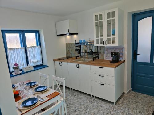 une cuisine avec des placards blancs et une table avec des assiettes. dans l'établissement Gorgova Delta Village, à Gorgova