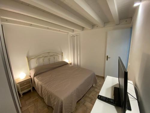 a bedroom with a bed and a desk with a television at Marisa’s House in Cefalù