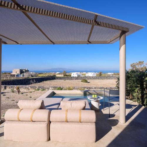 a patio with two white couches and a view of the beach at Santopaz Suites in Oia