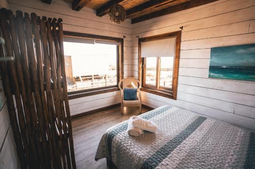 a bedroom with a bed and a window and a chair at Morros del Pacífico in Pichilemu