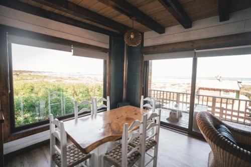 a dining room with a table and chairs and large windows at Morros del Pacífico in Pichilemu