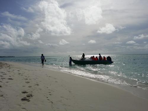 a group of people in a boat on the beach at Rasdhoo Coralville in Rasdu