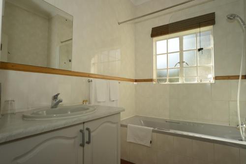 a white bathroom with a sink and a window at The Elegant Lodge Menlo Park in Pretoria