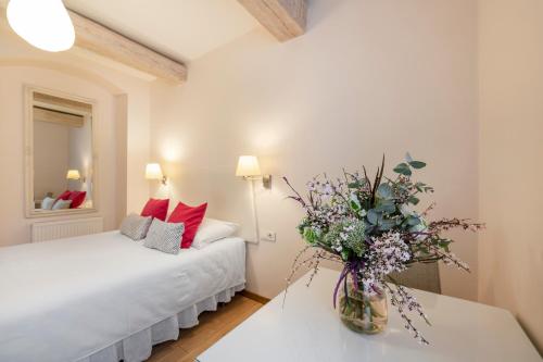 1 dormitorio con 1 cama y un jarrón de flores sobre una mesa en Guoda Apartments en Vilna