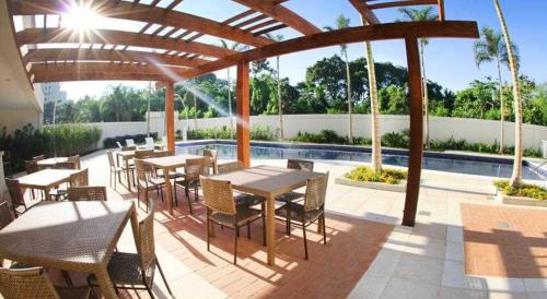 un patio avec tables et chaises à côté d'une piscine dans l'établissement Flat com Ótima infraestrutura, à Rio de Janeiro