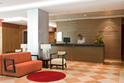 a lobby with a woman standing at the reception desk at Monte Gordo Hotel Apartamentos & Spa in Monte Gordo