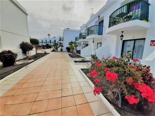 a walkway between two white buildings with red flowers at Casa Gil Corralejo San Valentin in Corralejo