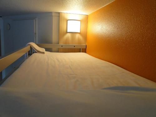 a large bed in a room with a light at Première Classe Nantes Sud - Rezé Aéroport in Rezé