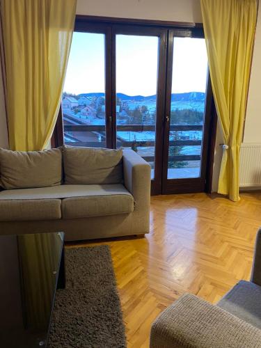 a living room with a couch and large windows at Zlatibor Tornik View in Zlatibor