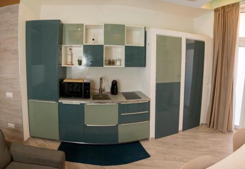 een keuken met groene kasten en een magnetron bij Catalani Charme Apartament in Cagliari