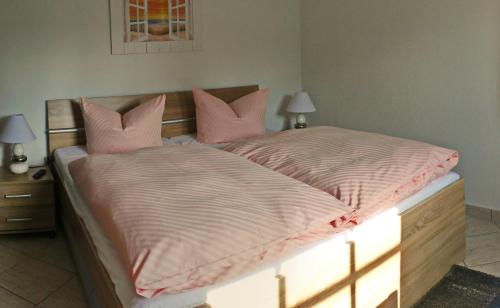 Schlafzimmer mit einem Bett mit rosa Bettwäsche und Kissen in der Unterkunft Haus Sonnenschein in Zingst