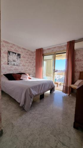 une chambre avec un grand lit et une grande fenêtre dans l'établissement Le République, à Cannes