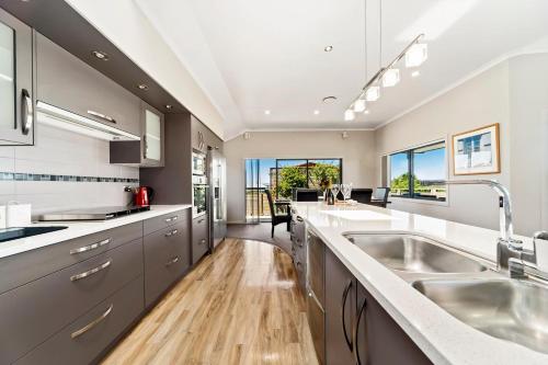 uma cozinha com balcões brancos e um grande lavatório em The Grand @ Taupo em Taupo