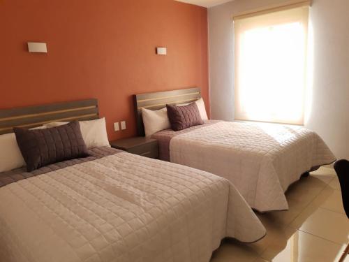 a hotel room with two beds and a window at H Rooms Hoteles Inn in La Piedad Cavadas