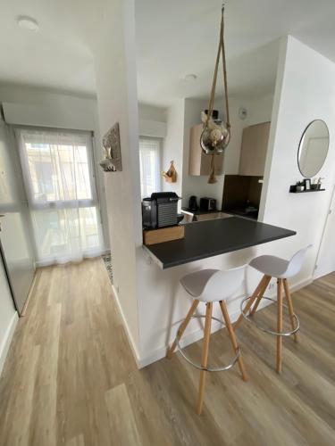 une cuisine avec un comptoir noir et deux tabourets dans l'établissement Appartement au centre historique de Nîmes, à Nîmes