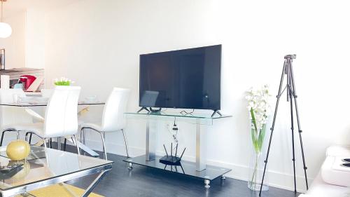 a living room with a television on a table with white chairs at Sky-Rise Apartments in Los Angeles