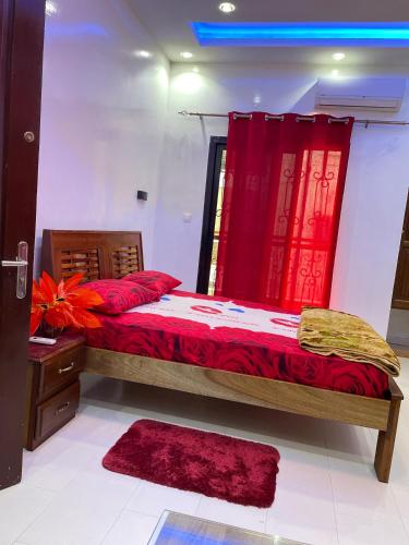 a bedroom with a bed with red sheets and red curtains at Villa soleil du Sénégal in Dakar