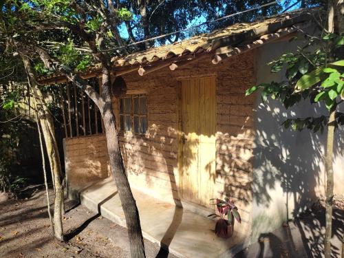 a wooden house with a door and a tree at Recanto da Alice in Trancoso