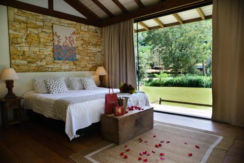 a bedroom with a bed and a large window at Pousada Boutique Itaipava in Itaipava