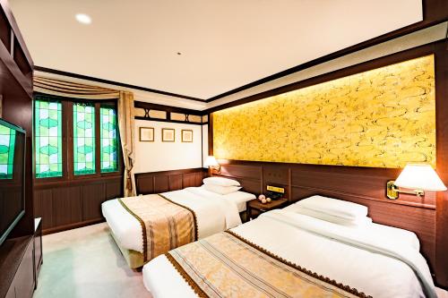 Habitación con 3 camas y pared amarilla. en Kanazawa Hakuchoro Hotel Sanraku, en Kanazawa