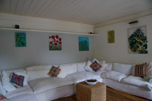 a living room with a white couch and paintings on the wall at Pousada Boutique Itaipava in Itaipava