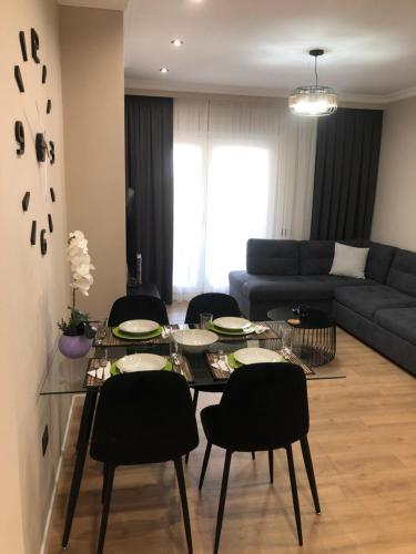 uma sala de estar com uma mesa e cadeiras e um sofá em Rooftop Sunset View Apartment em Tirana