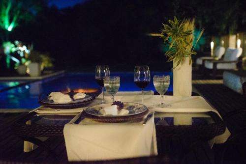 a table with two plates of food and wine glasses at Pousada Boutique Itaipava in Itaipava