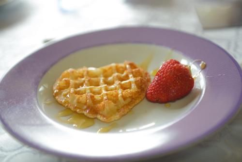 a white plate with waffles and a strawberry on it at Pousada Boutique Itaipava in Itaipava