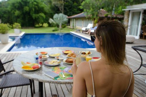 a woman sitting at a table with a tray of food at Pousada Boutique Itaipava in Itaipava