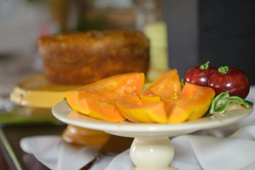 a plate of fruit on a table with a cake at Pousada Boutique Itaipava in Itaipava