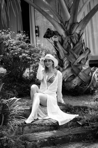 a woman in a white dress and hat sitting on a log at Pousada Boutique Itaipava in Itaipava