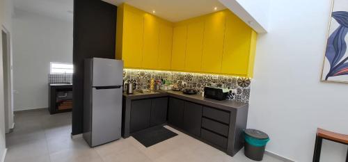 a kitchen with yellow cabinets and a refrigerator at Guesthouse @ Ipoh garden II in Ipoh