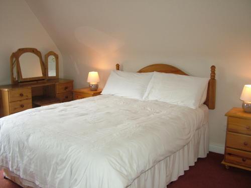 a bedroom with a white bed with two dressers and two lamps at Quarry Ridge B&B in Carlow