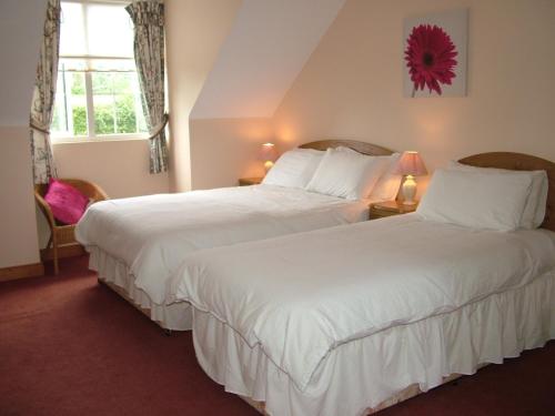 2 camas en una habitación de hotel con sábanas blancas en Quarry Ridge B&B, en Carlow
